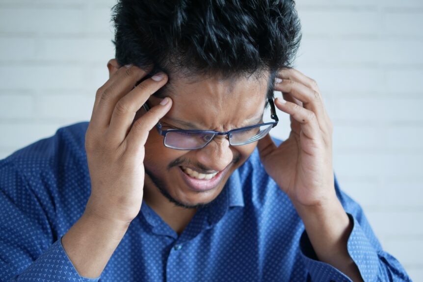 a man in long blue sleeves experiencing a new daily persistent headache